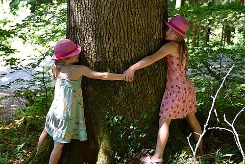Two young girls hugging a tree